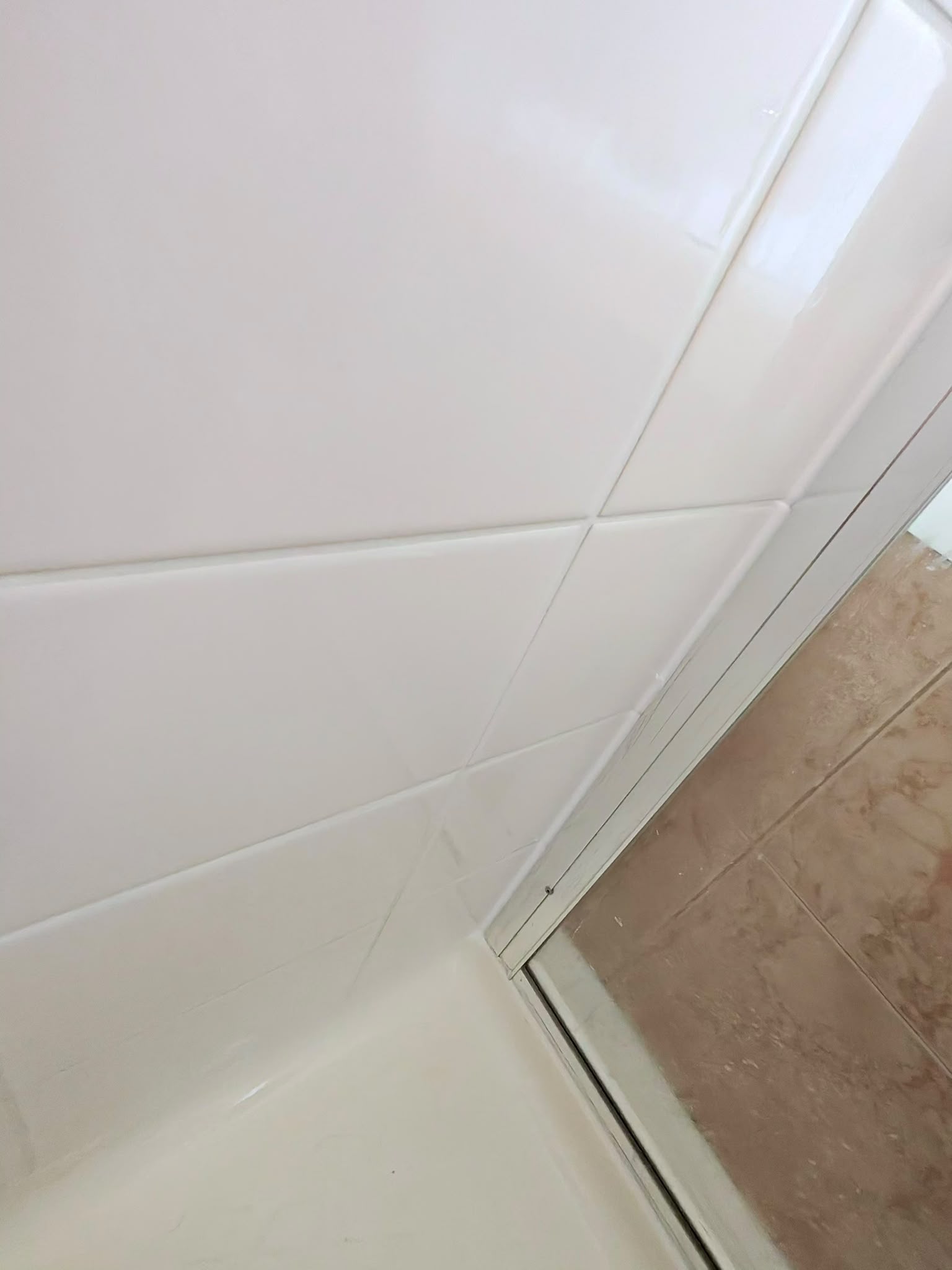 Restored white shower wall tile joints and clean polymarble base junction — Melbourne