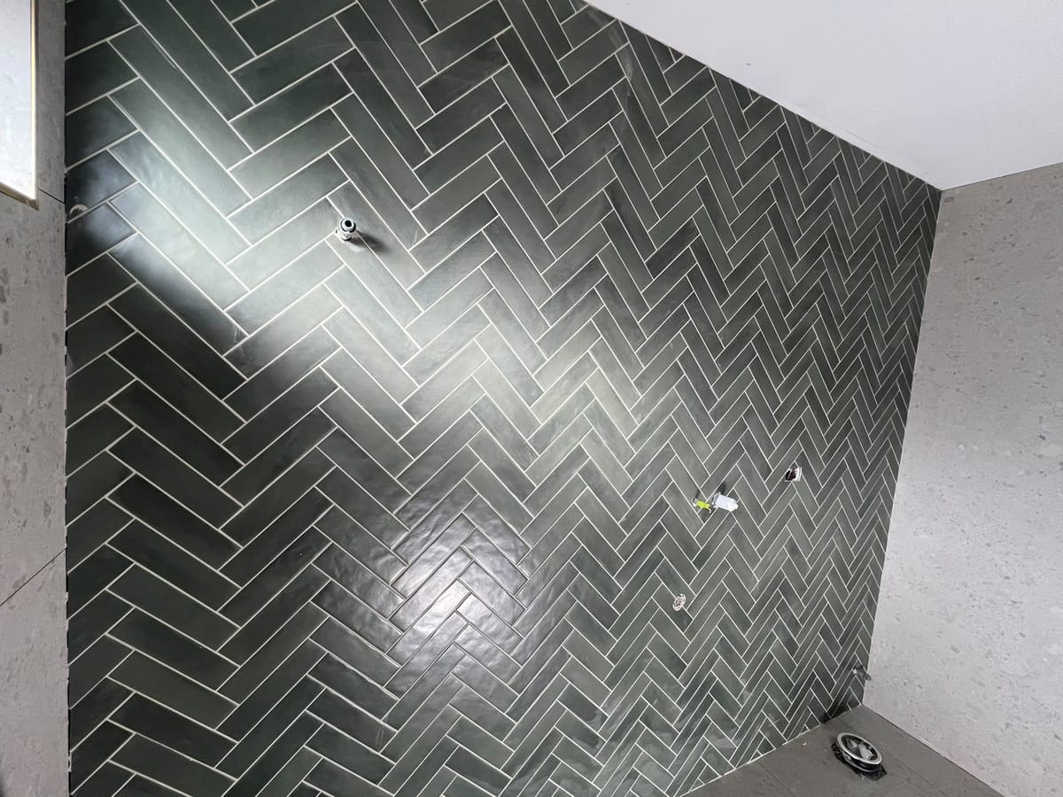 Completed green herringbone feature wall and grey bathroom floor tiling — Melbourne