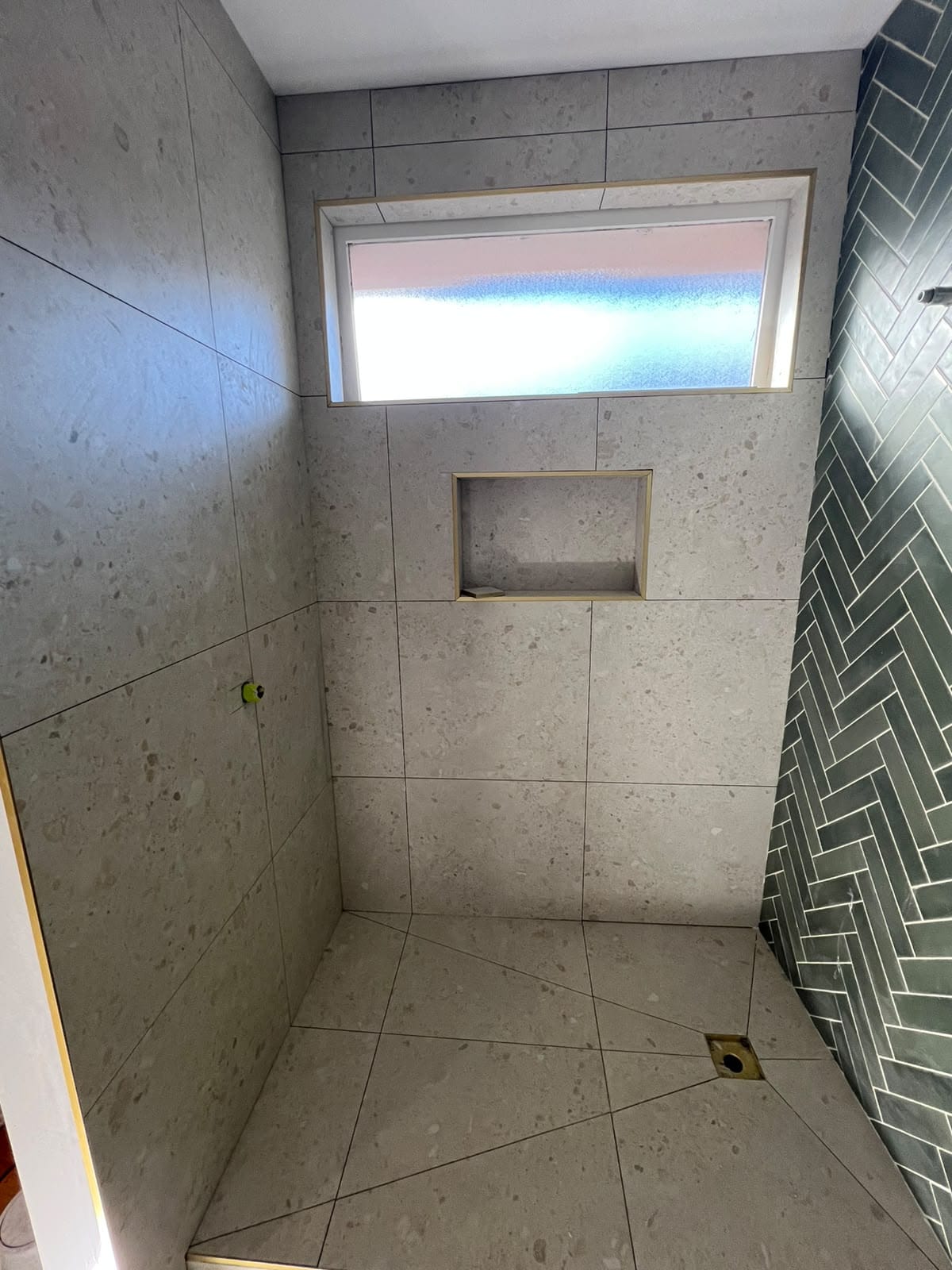 Completed bathroom tiling with green herringbone feature wall and tiled shower niche — Melbourne