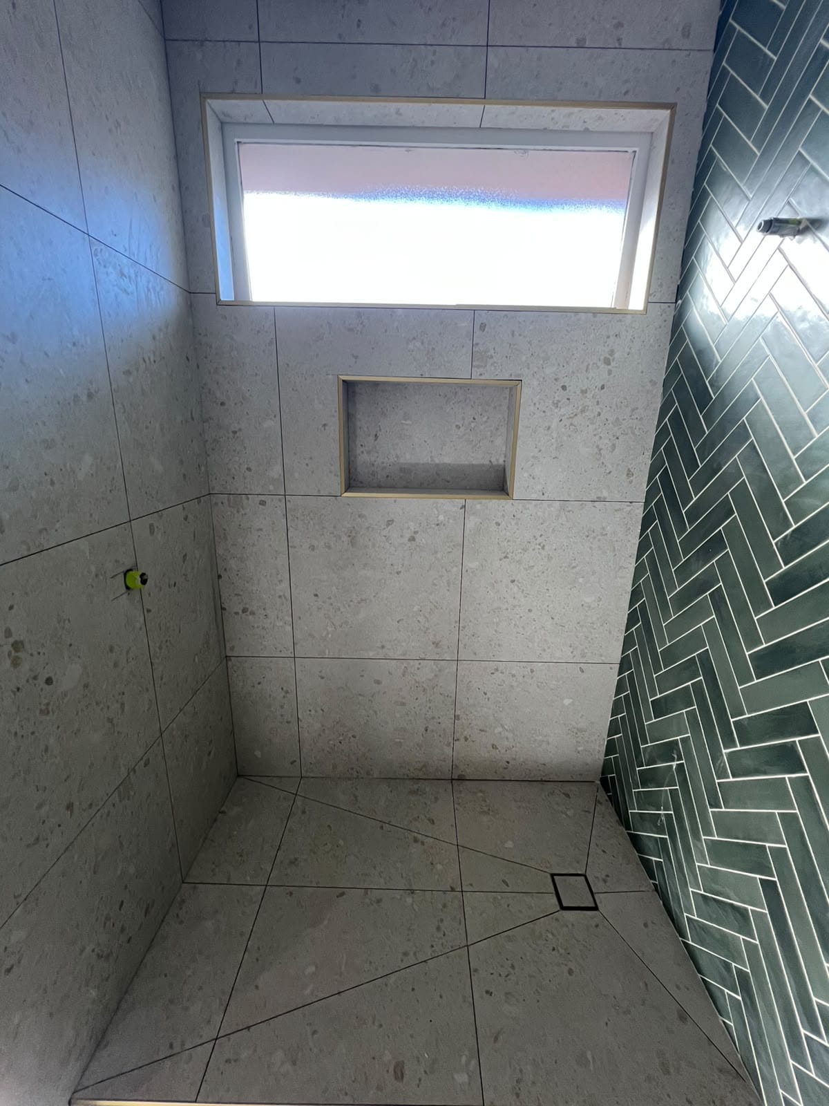 Tiled recessed shower niche, large-format grey wall tiles, and green herringbone wall — Melbourne
