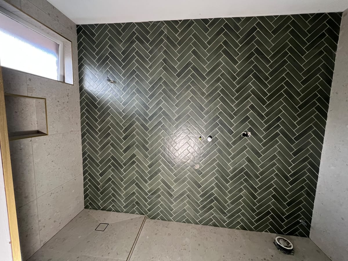 Completed bathroom shower floor tiling with linear strip drain and herringbone feature wall — Melbourne