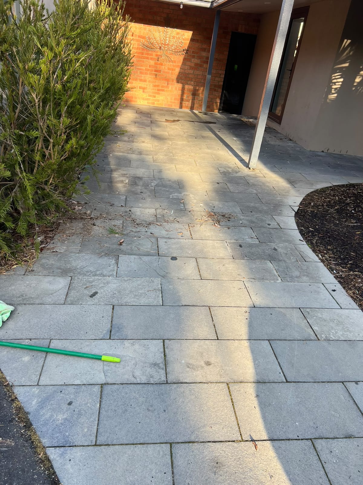 Outdoor grey paver pathway with open ungrouted joints before restoration — Melbourne
