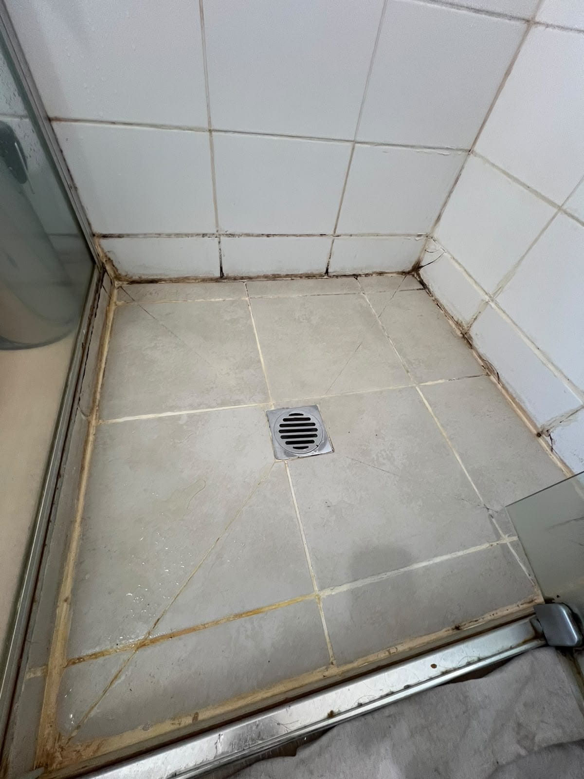 Shower floor tiles with discoloured grout and mouldy perimeter silicone — Melbourne