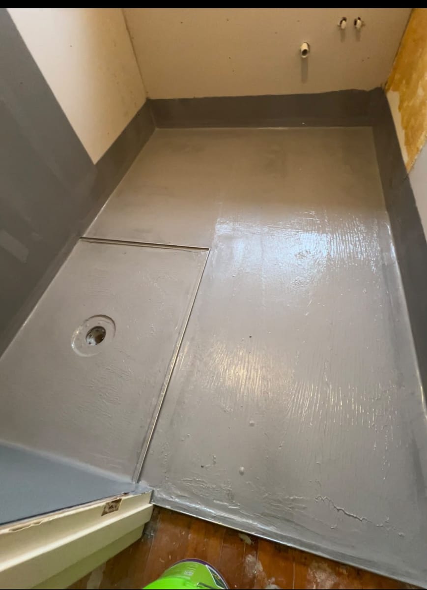 Tiler using an epoxy float to firmly pack resin grout into shower floor joints